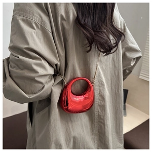 Red chrome crescent bag with circular cutout handle and gold chain strap on model