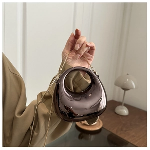 Detail of dark brown acrylic crescent bag with metallic mirror finish and gold chain strap
