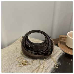 Detailed close-up of dark brown mirror-finish handbag with golden metal chain