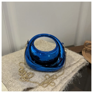 Detail of metallic blue crescent handbag with golden chain strap on plush texture