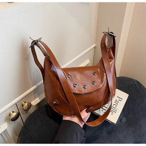 Détail d'un sac hobo en cuir marron avec clous argentés et texture souple raffinée