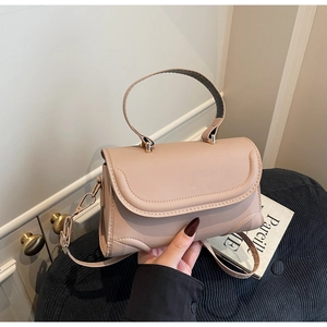 Detail of nude pink leather handbag showing fine stitching and gold metal buckle strap