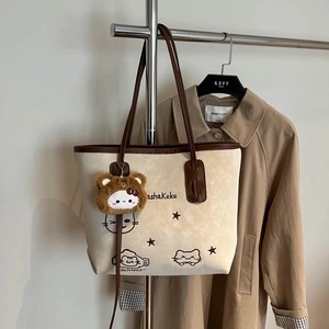 Grote beige tote bag met kattenprints en bruine riemen op een stijlvolle trenchcoat