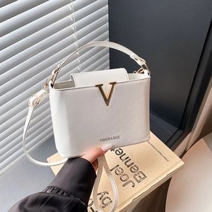 Minimalist white leather bucket bag with gold V-hardware and shoulder strap