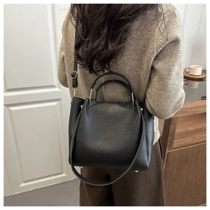 Close-up of black lychee grain texture tote bag with golden metal rings and shoulder strap