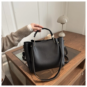 Detail of black lychee texture tote bag with gold metal hardware and adjustable strap