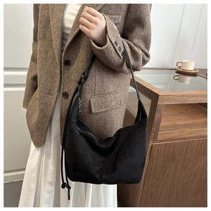Detail of a black suede hobo bag styled with a tweed blazer for a chic daily outfit