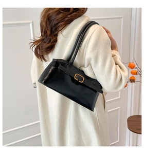 Détail d'un sac à bandoulière en cuir verni noir avec boucle dorée et double bandoulière