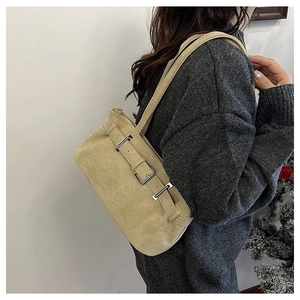 Detail of vintage beige suede underarm bag with metal buckle straps on a model