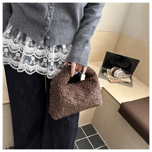 Close-up of brown faux fur handbag showing teddy fleece texture and curved handle details