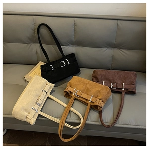 Close-up of four suede shoulder bags with metal buckle straps in various retro colors
