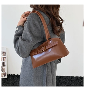 Sac porté épaule vintage en cuir marron avec boucle, porté par un mannequin en manteau de tweed