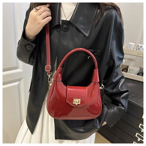 Detail of red patent leather crescent bag with golden rectangular twist lock and strap