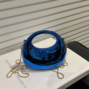 Chic metallic blue crescent handbag with gold chain strap on a white book