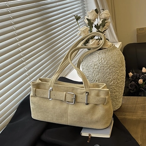 Retro beige suede underarm bag with vintage metal buckle shown in a warm indoor setting