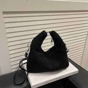 Black plush teddy fleece Hobo handbag on white book with silver hardware and strap