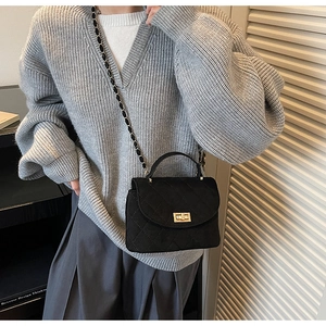 Gros plan sur le sac matelassé noir avec fermoir doré et bandoulière en chaîne