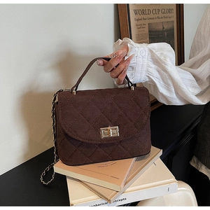 Close-up of quilted corduroy mini bag with golden twist lock and chain strap detail