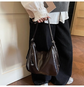Close-up of dark coffee leather hobo bag with front zipper detail and brand logo