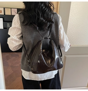 Detail view of large dark brown leather backpack with silver logo and side zipper