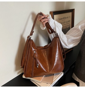 Detailed view of caramel brown leather tote bag with front zipper and fashion text