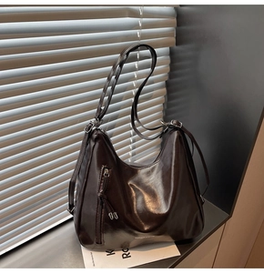 Detail of dark brown glossy PU leather tote bag with vertical zipper and adjustable strap