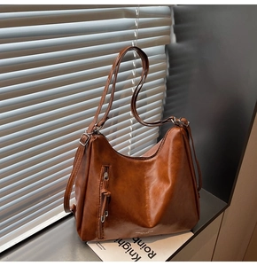 Close-up of brown vintage leather tote bag with vertical zipper and adjustable strap
