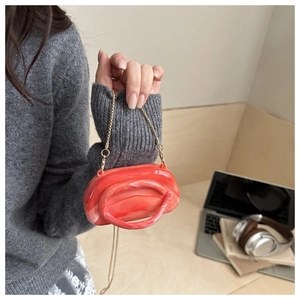 Detail of orange marble acrylic clutch bag with gold chain strap in urban lifestyle setting