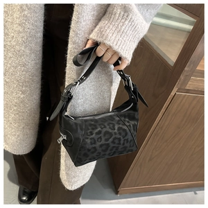 Close-up of leopard print tote bag featuring black leather trim and silver buckle strap