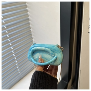Detail of blue marble acrylic mini evening bag with elegant gold chain and top handle