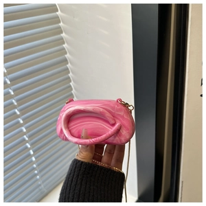 Detail of pink marble acrylic evening bag with elegant gold metal chain strap