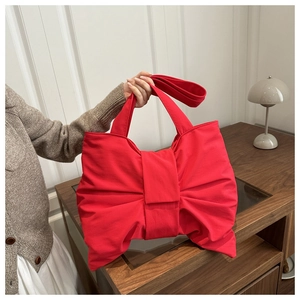Detail of red bow-shaped nylon shoulder bag with soft matte texture and fabric handle