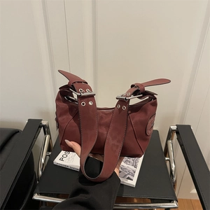 Retro burgundy tote bag with wide shoulder straps and silver buckles on a dark leather seat