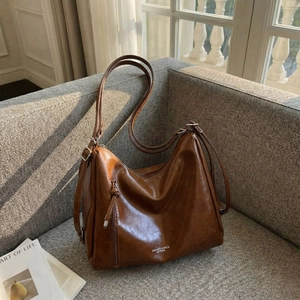 Brown large capacity leather tote bag with long straps on a sofa in a bright room