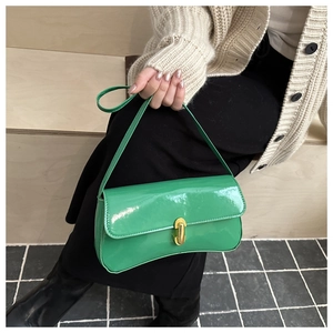 Dettaglio della borsa sottobraccio in vernice verde brillante con fibbia dorata
