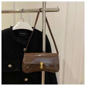 Close-up of a glossy brown PU leather crossbody bag with a gold twist lock on tweed jacket