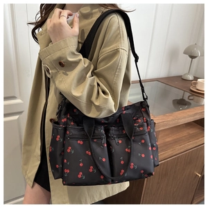 Detail of black nylon tote bag with red cherry print and functional zipper pockets