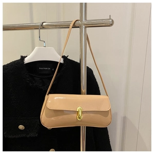 Close-up of beige patent leather baguette bag with elegant golden oval metal twist lock