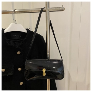 Detail of glossy black patent leather shoulder bag with elegant gold U-shaped metal lock
