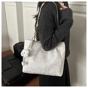 Detail of white tote bag featuring embossed texture and chic plush cloud pendant accessory