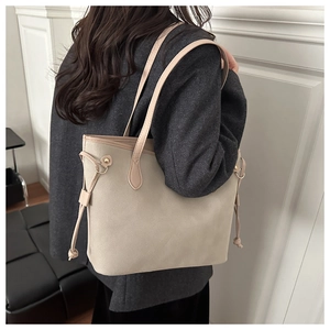 Detail of beige tote bag side drawstring and metal ring on matte textured material
