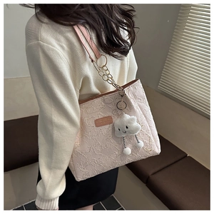 Detail of pink jacquard tote bag with metal chain strap and cloud plush charm detail
