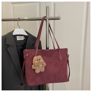Detail of burgundy frosted tote bag with a cute plush bear charm on a metal hanger