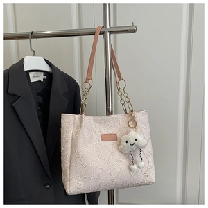 Close-up of star-quilted pink leather tote bag featuring a cute plush cloud charm