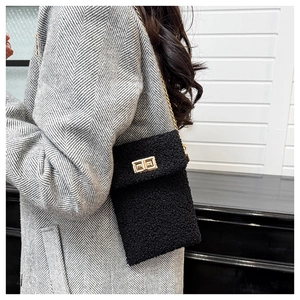 Detail of black faux fur plush crossbody bag with gold chain strap and metal clasp