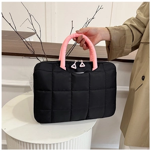 Close-up of black quilted briefcase with pink handles and triangular zip puller