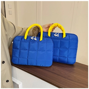 Detail of blue quilted laptop bag featuring yellow ruched handles and durable fabric
