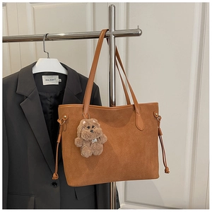 Detail of brown faux suede tote bag with drawstring side and plush dog pendant