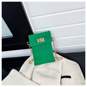 Detalle de bolso bandolera verde esmeralda acolchado con cadena dorada y cierre de giro