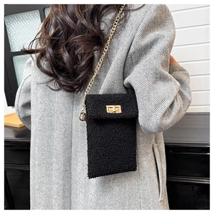 Detail of plush black crossbody phone bag featuring a gold chain strap and metal turn-lock